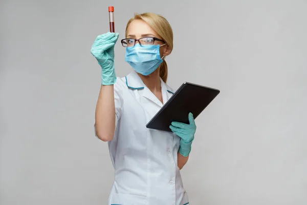 Verpleegkundige vrouw met beschermend masker en handschoenen - met virusbloedtest en tablet pc — Stockfoto