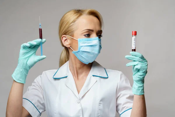 Médico enfermera mujer con máscara protectora y guantes - análisis de sangre y jeringa del virus de la celebración —  Fotos de Stock
