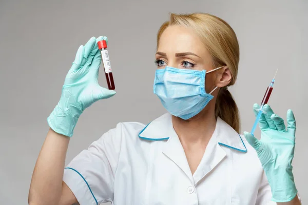 Verpleegkundige vrouw met beschermend masker en handschoenen - met virusbloedtest en injectiespuit — Stockfoto