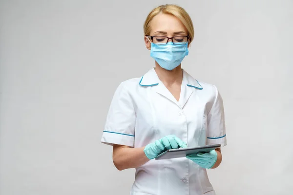 Medische arts verpleegkundige vrouw met beschermend masker en handschoenen - tablet vasthouden pc — Stockfoto