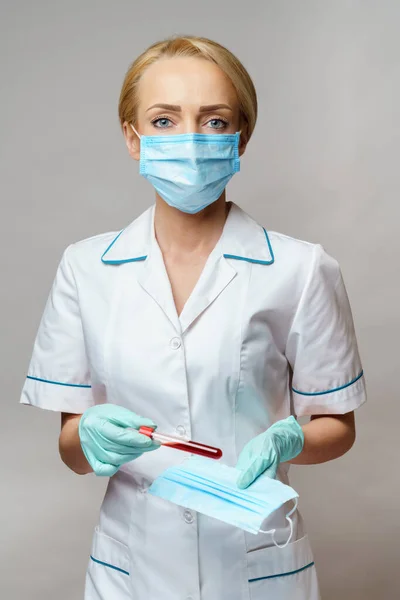 Verpleegkundige vrouw met latex handschoenen - met virusbloedtest en beschermend masker — Stockfoto