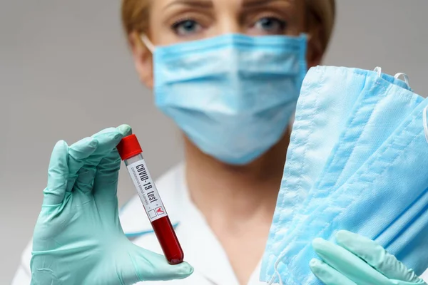 Médico enfermeira mulher vestindo luvas de látex - segurando vírus teste de sangue e máscara protetora — Fotografia de Stock