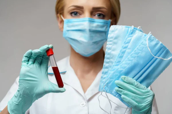 Verpleegkundige vrouw met latex handschoenen - met virusbloedtest en beschermend masker — Stockfoto