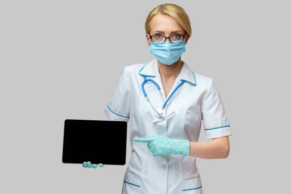 Médico médico enfermera mujer con máscara protectora y guantes - la celebración de la tableta de PC —  Fotos de Stock