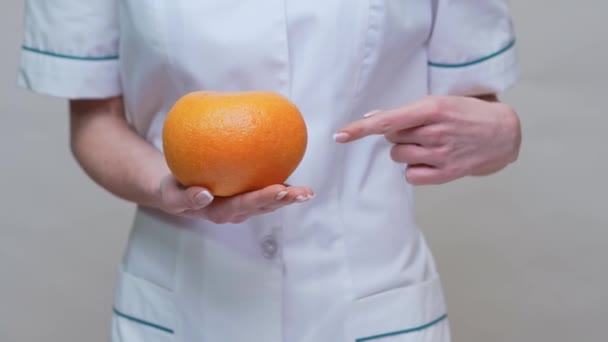 Dietetyk lekarz zdrowy styl życia koncepcja - trzymając organiczne owoce grejpfruta i taśmę pomiarową — Wideo stockowe