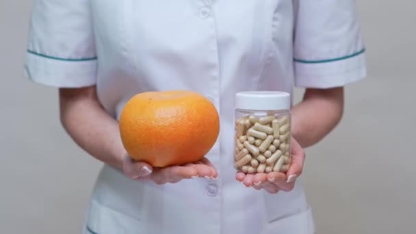 Nutritionist doctor healthy lifestyle concept - holding organic grapefruit and jar of vitamin pills — Stock Video