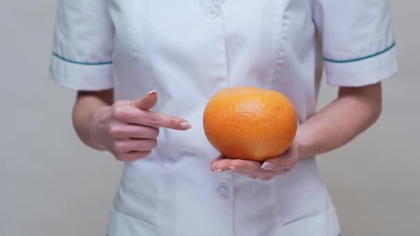 Дієтолог концепція здорового способу життя - тримає грейпфрут і ліки або вітамінну таблетку — стокове відео