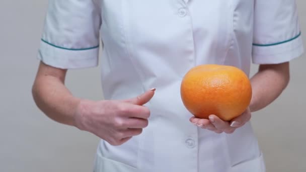 Nutricionista médico concepto de estilo de vida saludable - celebración de pomelo y medicamentos o píldoras vitamínicas — Vídeos de Stock