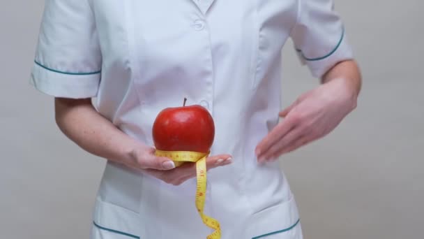 Nutritionniste médecin mode de vie sain concept - tenant pomme rouge biologique et ruban à mesurer — Video