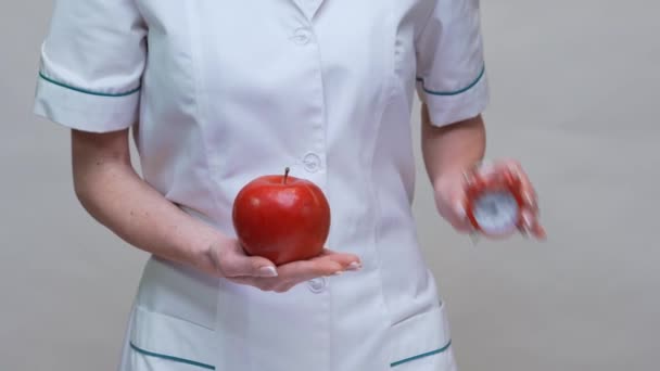 Dietetyk lekarz zdrowy styl życia koncepcja - gospodarstwa organiczne czerwone jabłko i budzik — Wideo stockowe