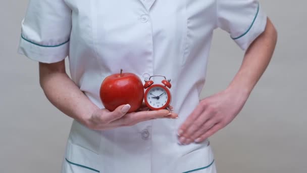 Concepto de estilo de vida saludable médico nutricionista - la celebración de manzana roja orgánica y despertador — Vídeos de Stock