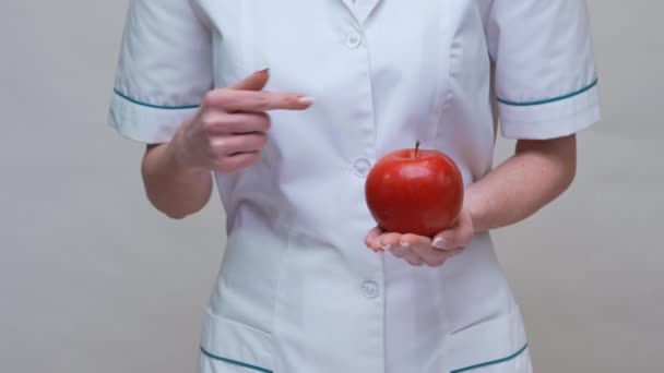 Nutritionist doctor healthy lifestyle concept - holding red apple and medicine or vitamin pill — Stock Video