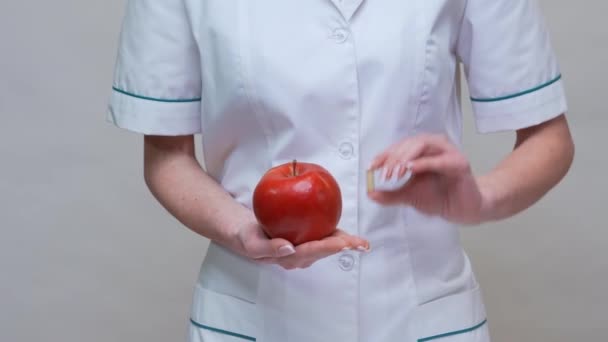 Концепция здорового образа жизни врача-диетолога - проведение красного яблока и лекарства или витаминов — стоковое видео