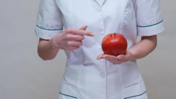 Диетолог-врач понятие здорового образа жизни - проведение красного яблока и лекарства или витамины таблетки — стоковое видео