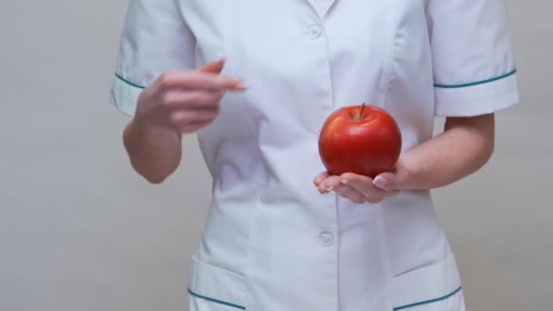 Nutritionist doctor healthy lifestyle concept - holding red apple and medicine or vitamin pills — Stock Video