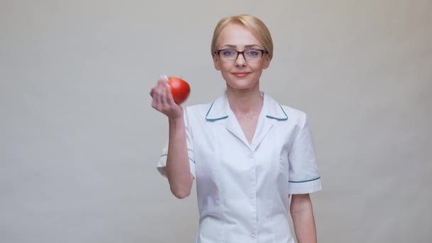 Nutritionist doctor healthy lifestyle concept - holding organic red apple and alarm clock — Stock Video