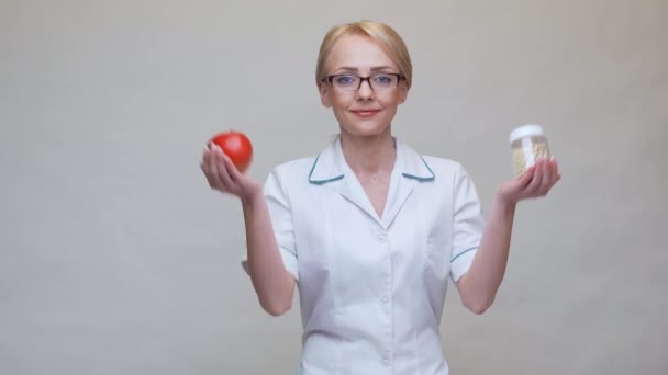 Diyetisyen doktor sağlıklı yaşam tarzı konsepti - organik kırmızı elma ve bir kavanoz vitamin hapı — Stok video