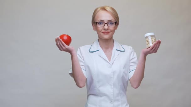 Дієтолог концепція здорового способу життя - тримає органічне червоне яблуко і банку вітамінних таблеток — стокове відео