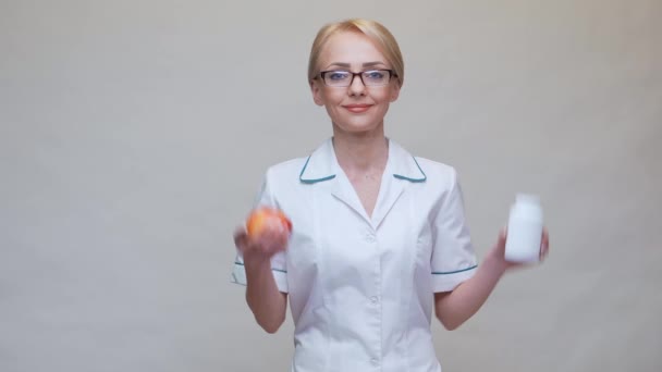 Nutricionista médico concepto de estilo de vida saludable - sosteniendo manzana roja orgánica y frasco de píldoras vitamínicas — Vídeos de Stock