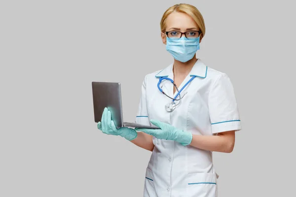 Verpleegkundige vrouw met beschermend masker en handschoenen - laptop vasthouden — Stockfoto