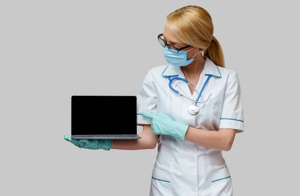 Médico médico enfermera mujer con máscara protectora y guantes - portátil de celebración —  Fotos de Stock