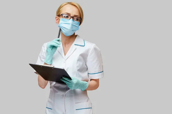 Médico o enfermera sosteniendo mesa plana y pluma —  Fotos de Stock