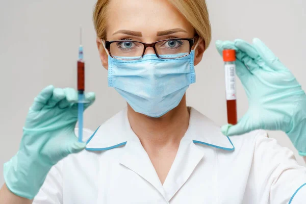 보호 마스크를 쓰고 주사기와 혈액 검사 튜브를 들고 있는 의사나여 간호사 — 스톡 사진