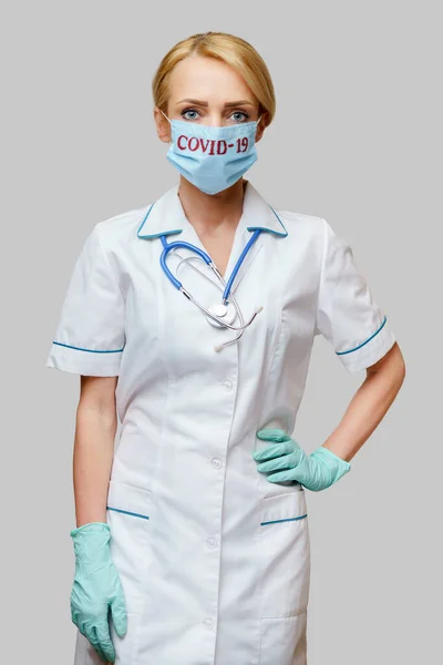 Врач-женщина со стетоскопом в защитной маске и латексных перчатках на светло-сером фоне — стоковое фото