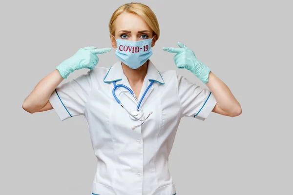 Femme médecin avec stéthoscope portant un masque protecteur et des gants en latex sur fond gris clair — Photo