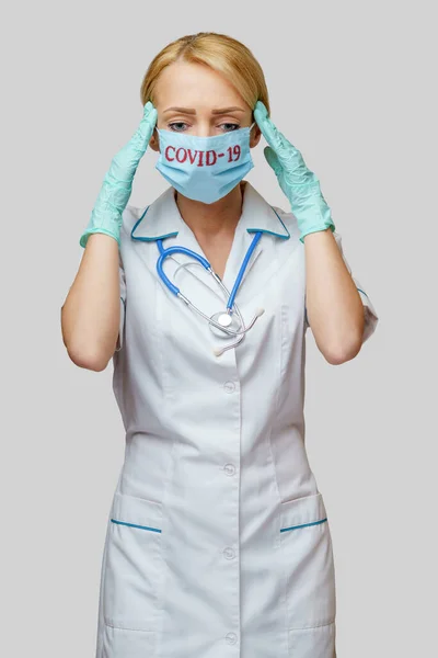 Врач медсестра женщина в защитной маске и резиновых или латексных перчатках - головная боль и стресс — стоковое фото