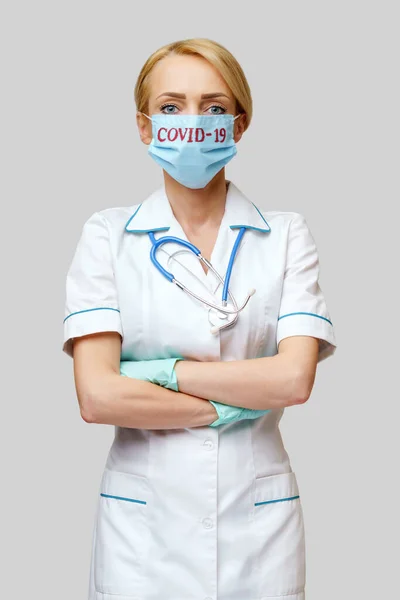 Врач-женщина со стетоскопом в защитной маске и латексных перчатках на светло-сером фоне — стоковое фото