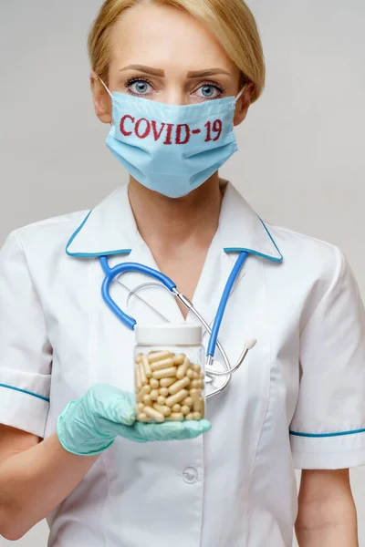 Врач медсестра женщина в защитной маске и резиновых или латексных перчатках - держание банка с таблетками — стоковое фото