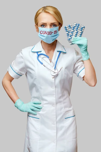Врач медсестра женщина в защитной маске и резиновых или латексных перчатках - проведение волдыри таблетки — стоковое фото