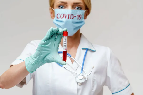 Médico enfermeira mulher usando máscara protetora e luvas - segurando vírus tubo de teste de sangue — Fotografia de Stock