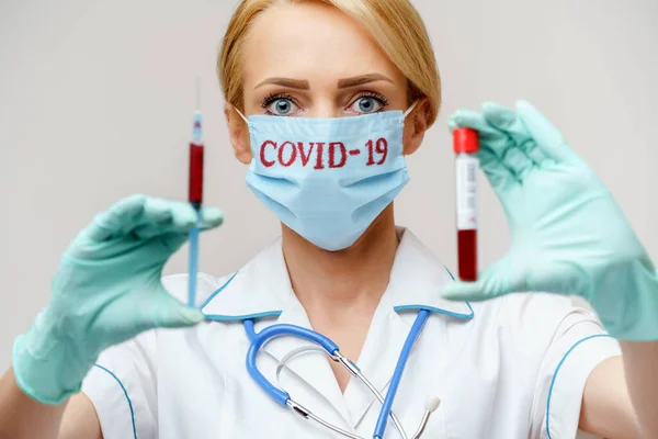 Врач медсестра женщина в защитной маске и перчатках - проведение пробирки крови вируса и шприц — стоковое фото