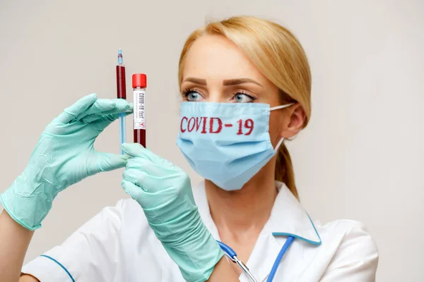 Medico infermiere donna con maschera e guanti protettivi - contenente la provetta e la siringa per l'analisi del sangue del virus — Foto Stock