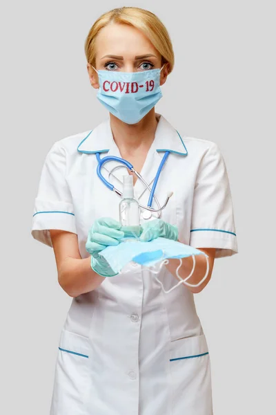 Médico enfermera mujer con estetoscopio - la celebración de máscara protectora y desinfectante —  Fotos de Stock