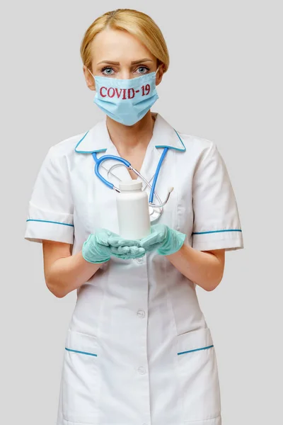 Medico infermiere donna con maschera protettiva e guanti di gomma o lattice - lattina contenente pillole — Foto Stock