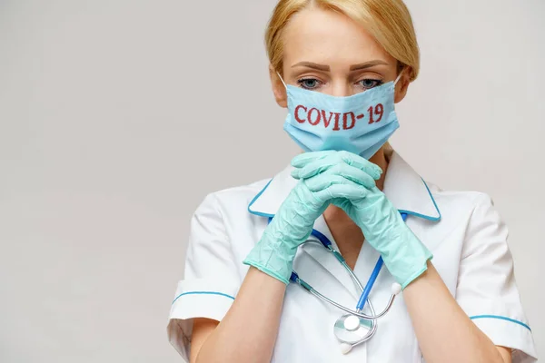Medico infermiera donna indossando maschera protettiva e guanti di lattice - pregare nad sperando gesto — Foto Stock