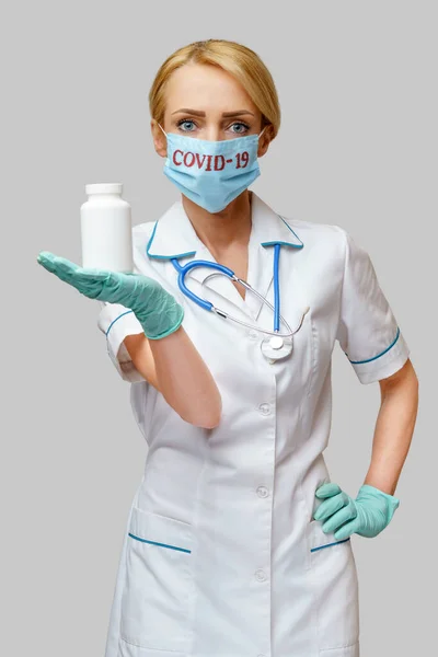 Medico infermiere donna con maschera protettiva e guanti di gomma o lattice - lattina contenente pillole — Foto Stock