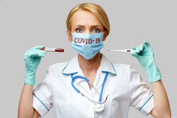 Врач медсестра женщина в защитной маске и резиновых или латексных перчатках - проведение термометра и пробирки крови вируса — стоковое фото