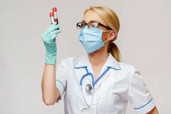 Läkare sjuksköterska kvinna bär skyddsmask och handskar - hålla virus blodprov — Stockfoto
