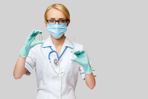 Verpleegkundige vrouw met beschermend masker en handschoenen - flesje met vaccin en spuit — Stockfoto