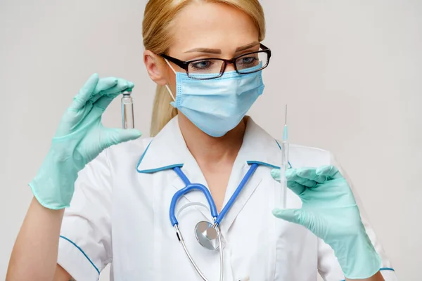 Läkare sjuksköterska kvinna bär skyddsmask och handskar - hålla flaska vaccin läkemedel och spruta — Stockfoto