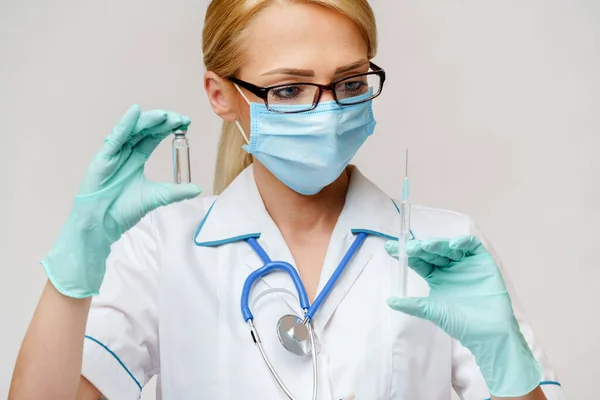 Verpleegkundige vrouw met beschermend masker en handschoenen - flesje met vaccin en spuit — Stockfoto