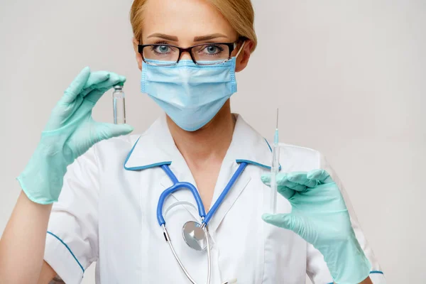 Verpleegkundige vrouw met beschermend masker en handschoenen - flesje met vaccin en spuit — Stockfoto