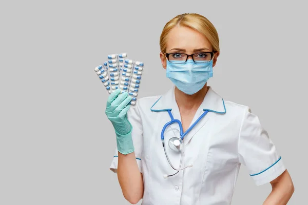 Verpleegkundige vrouw met beschermend masker en rubber of latex handschoenen - met blaren van pillen — Stockfoto