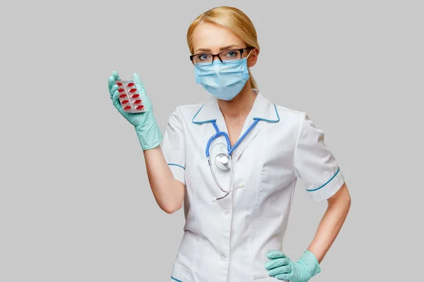 Médecin infirmière femme portant un masque protecteur et des gants en caoutchouc ou en latex - tenant des ampoules de pilules — Photo
