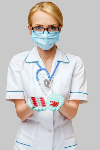 Лікар медсестра жінка в захисній масці і гумі або латексних рукавичках тримає пухирі таблеток — стокове фото