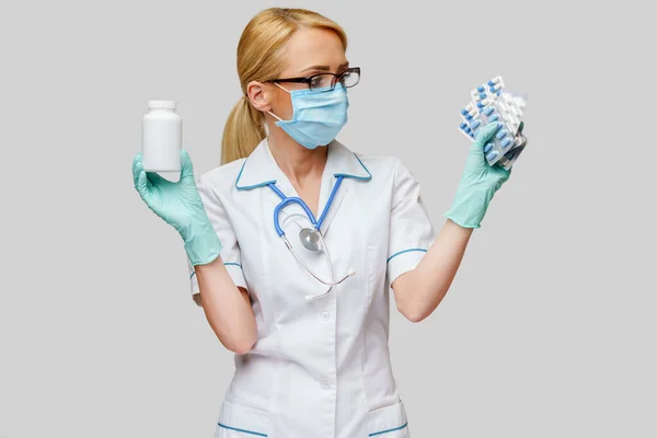 医療看護師の女性は、保護マスクやゴムやラテックス手袋を身に着けている-薬や錠剤の水疱の缶を保持 — ストック写真